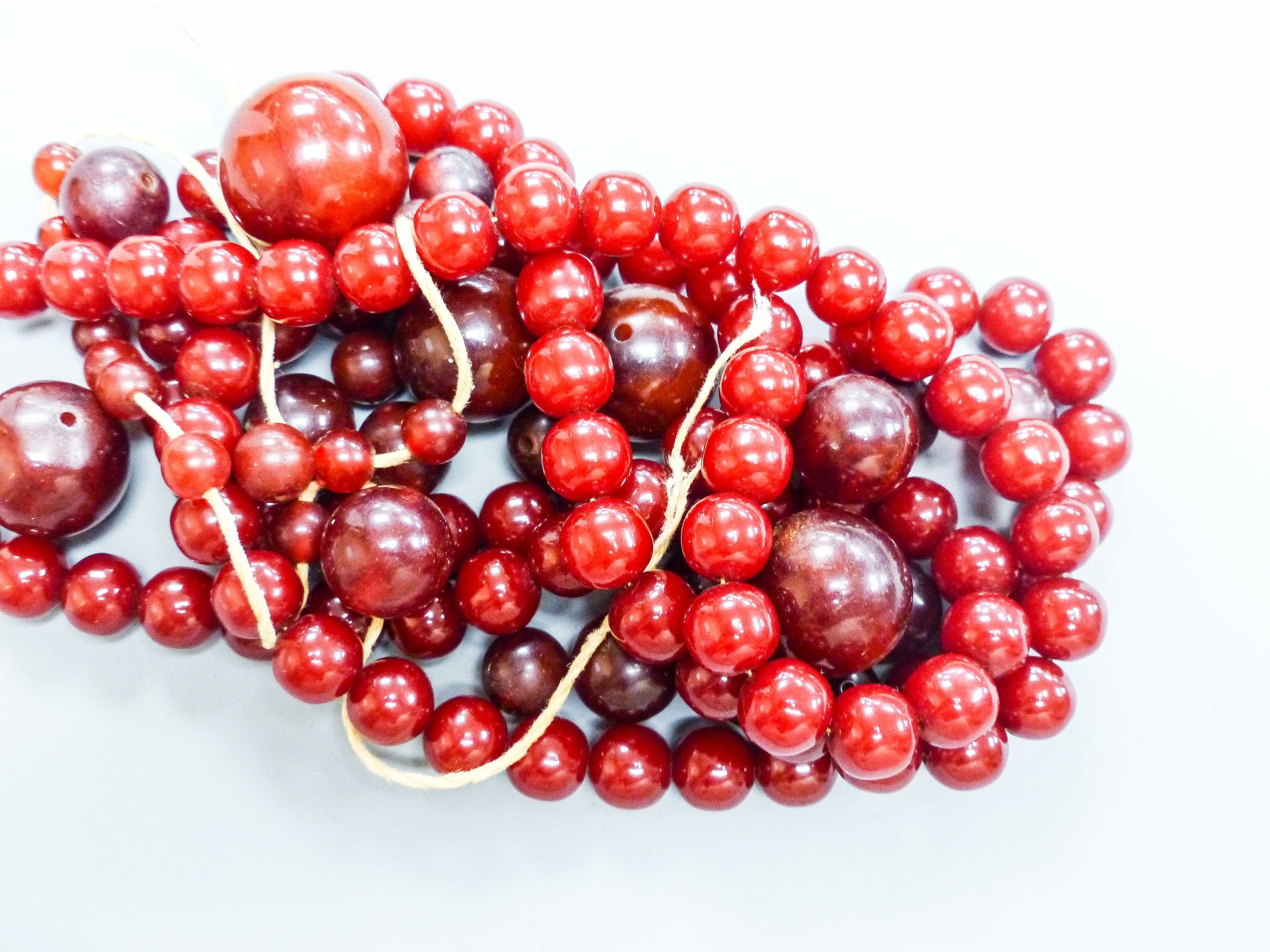 A group of loose simulated cherry amber beads and one other similar necklace, gross weight 254 grams.